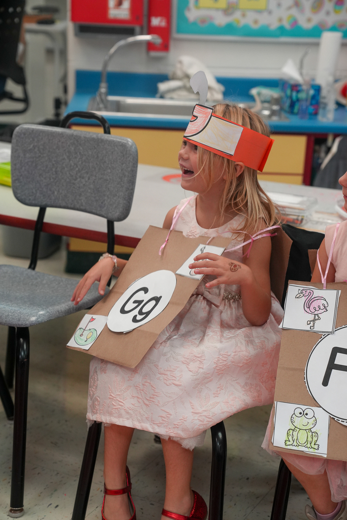 A kindergarten student wearing a handmade letter G costume smiles during the ABC fashion show.
