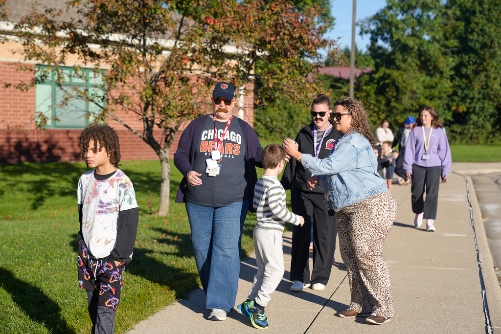 Students and staff walk outside Mulberry Elementary during the Random Attendance Day reward. Two staff members wear sunglasses and fake mustaches for “Secret Identity” spirit day.