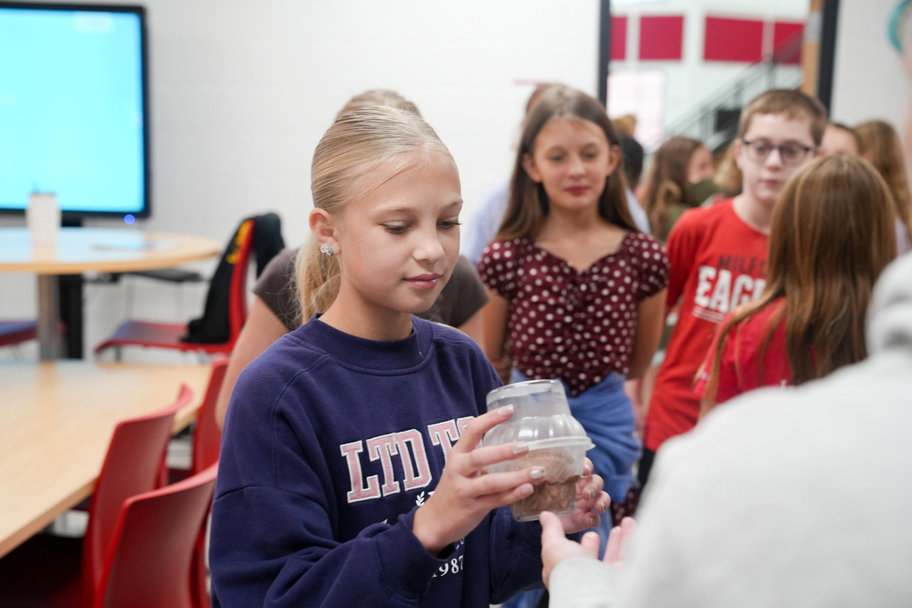 A student holds a cup of ice cream while classmates wait behind her during the ScoopAble classroom celebration.
