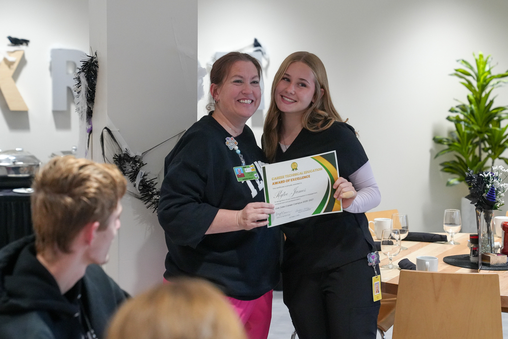 Milford student Kylee James poses with a Great Oaks Health Technology staff member while holding her Career Technical Education Award of Excellence certificate.