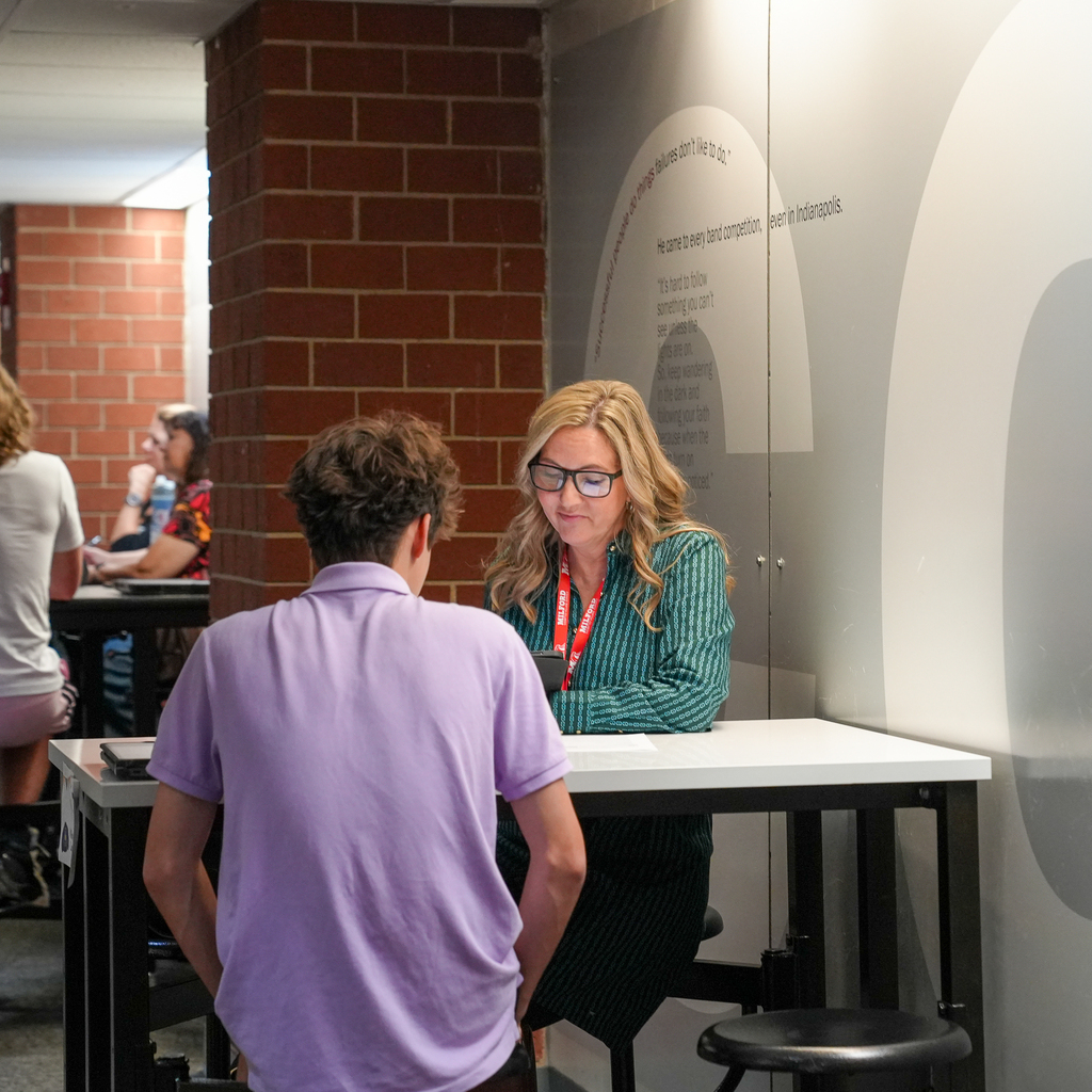A student holding papers and a folder shakes hands with an adult interviewer during an FFA career preparation activity at Milford High School.