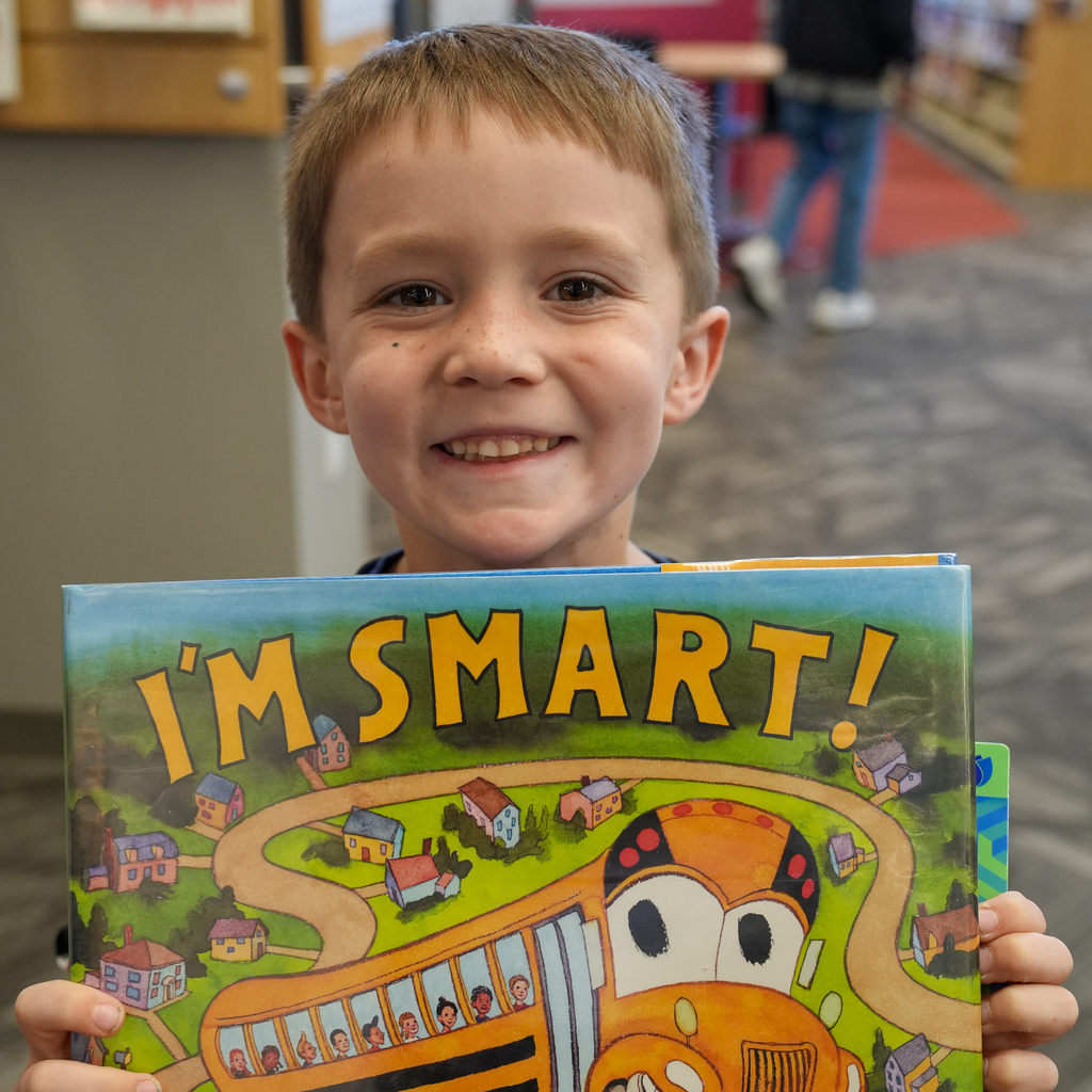 A smiling student holds up “I’m Smart!” featuring an illustrated school bus on the cover.