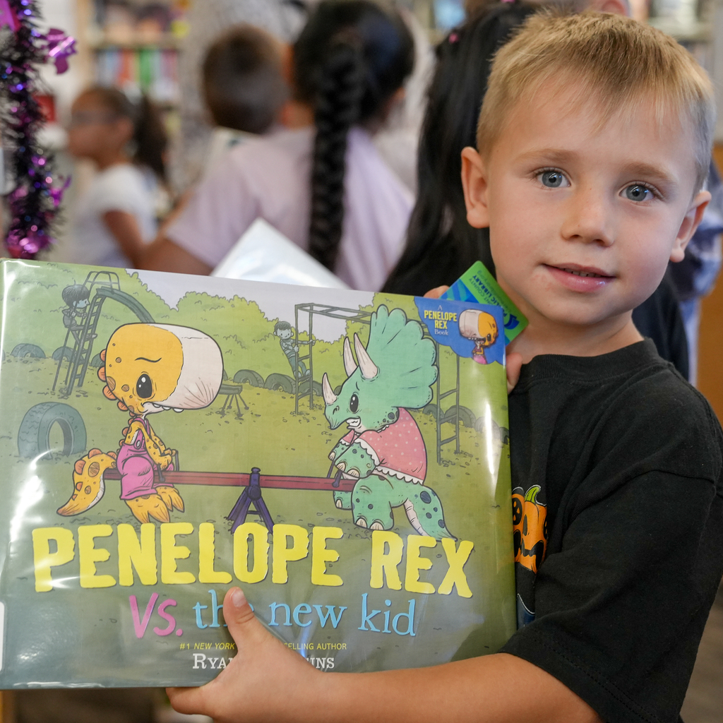 A Mulberry kindergarten student holds up “Penelope Rex vs. the New Kid” during a library visit.