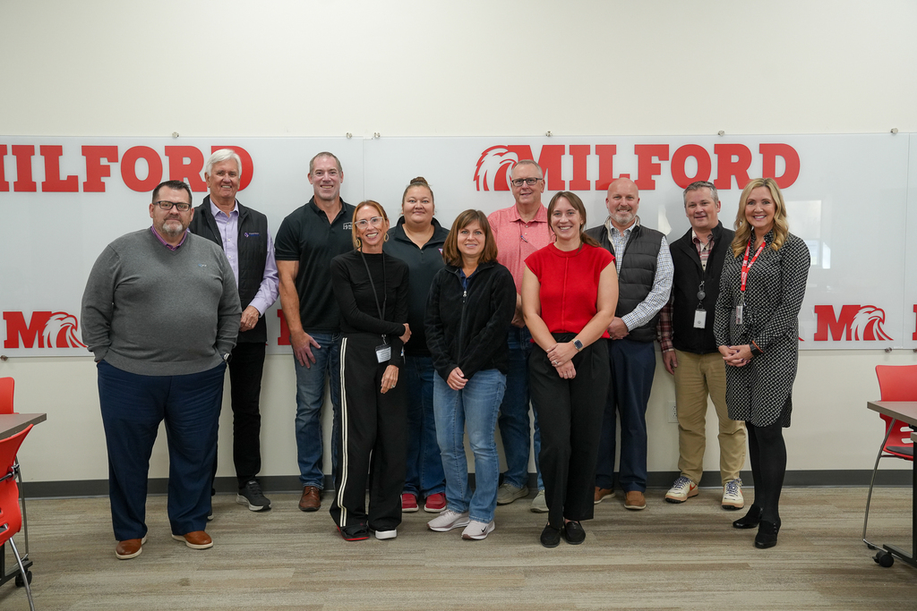 Eleven Business Advisory Council meeting participants pose together in front of red Milford lettering and Eagle logos.