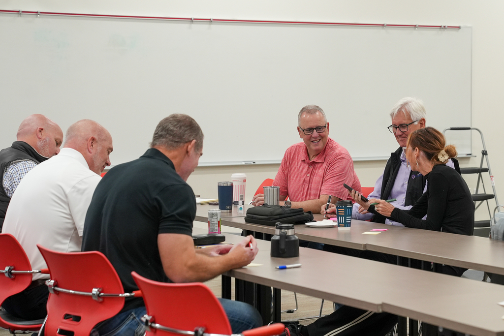 Business Advisory Council members sit around tables, sharing ideas and taking notes during a small-group discussion.