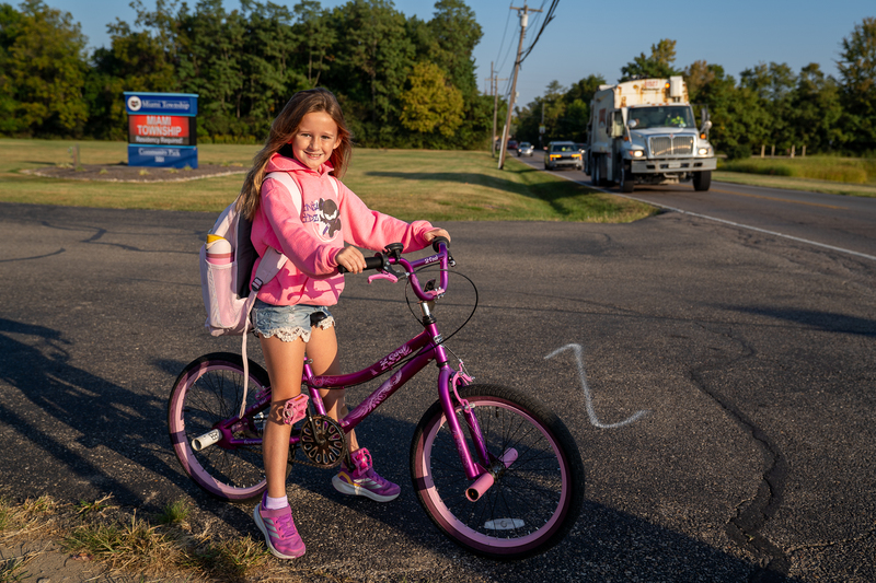 A student wearing a pink sweatshirt on a pink bike 