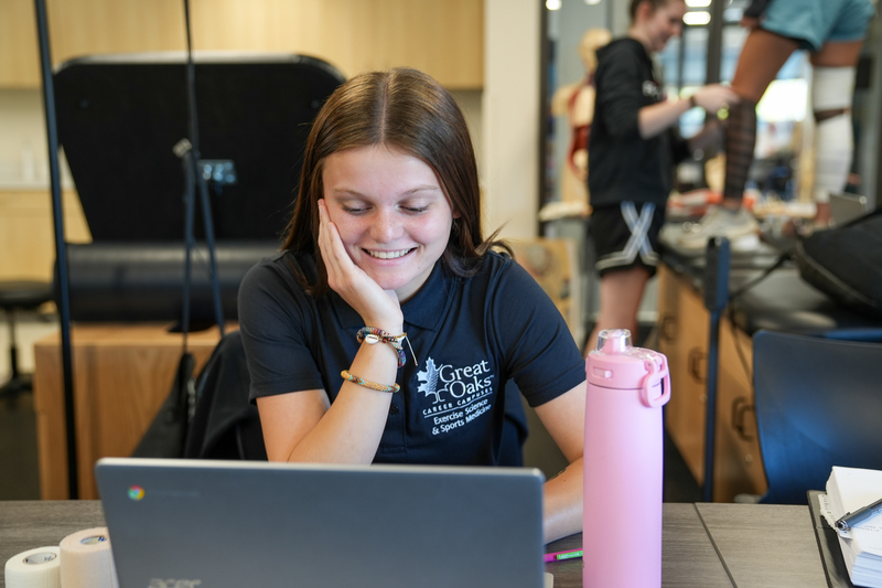 A student with a laptop at a desk smiling