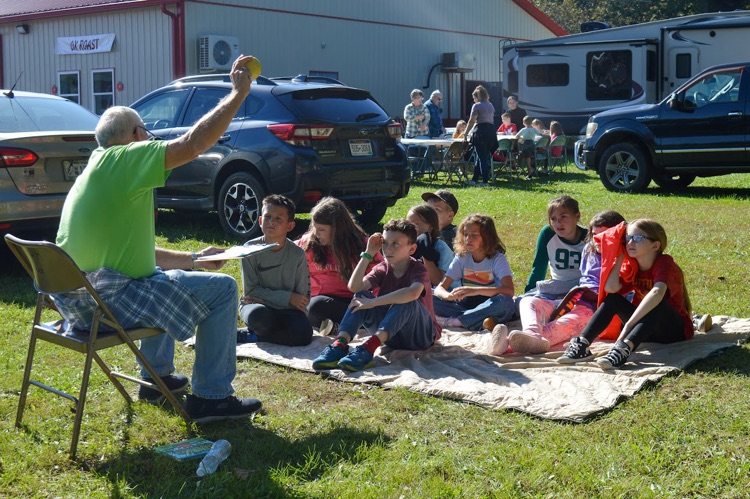 A photo of students listening to an Apple-themed story at the Apple Harvest. 