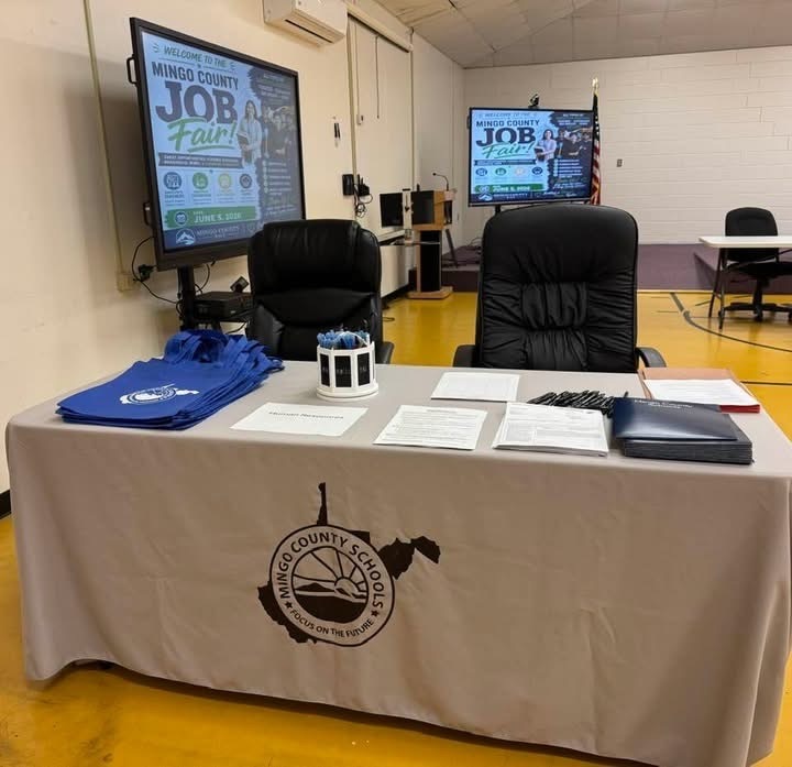 job fair with a table and a tan table cloth and smart tvs in the background