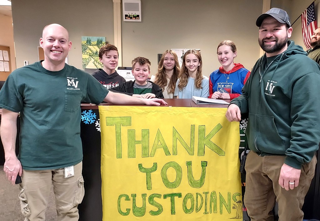 students and custodial staff with sign