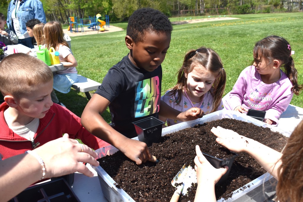 students putting dirt in a pot