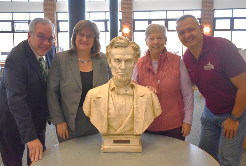 Four people with a bust of Abraham Lincoln