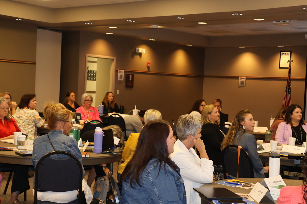 Female leaders sit in the room with their attention towards the speaker.