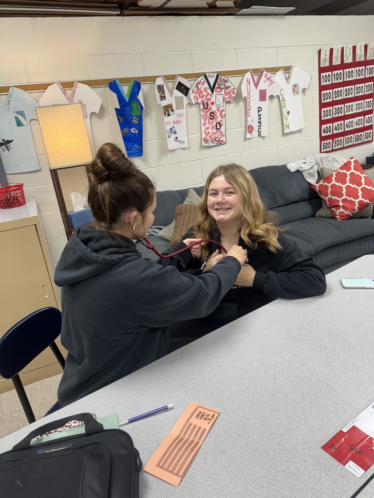 A student uses a stethoscope to listen to another student’s chest.