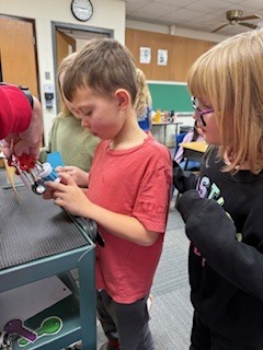 A young boy uses a lock while another student watches closely.