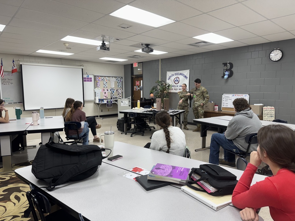 Students listen to two Iowa Army National Guard members giving a presentation in a health occupations classroom.