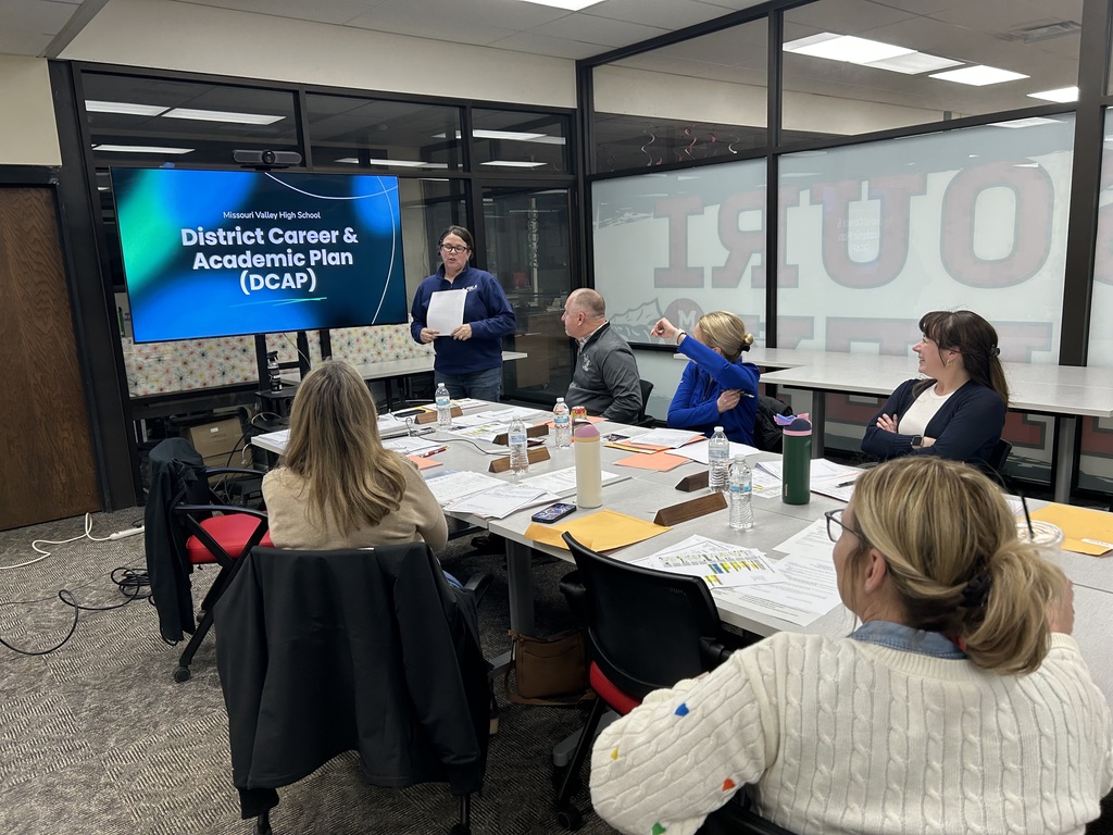 A staff member presents the District Career & Academic Plan to attendees in a conference setting.