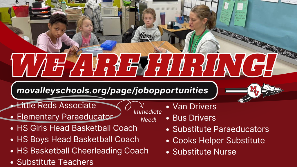 Photo of a teacher sitting at a table working with children.