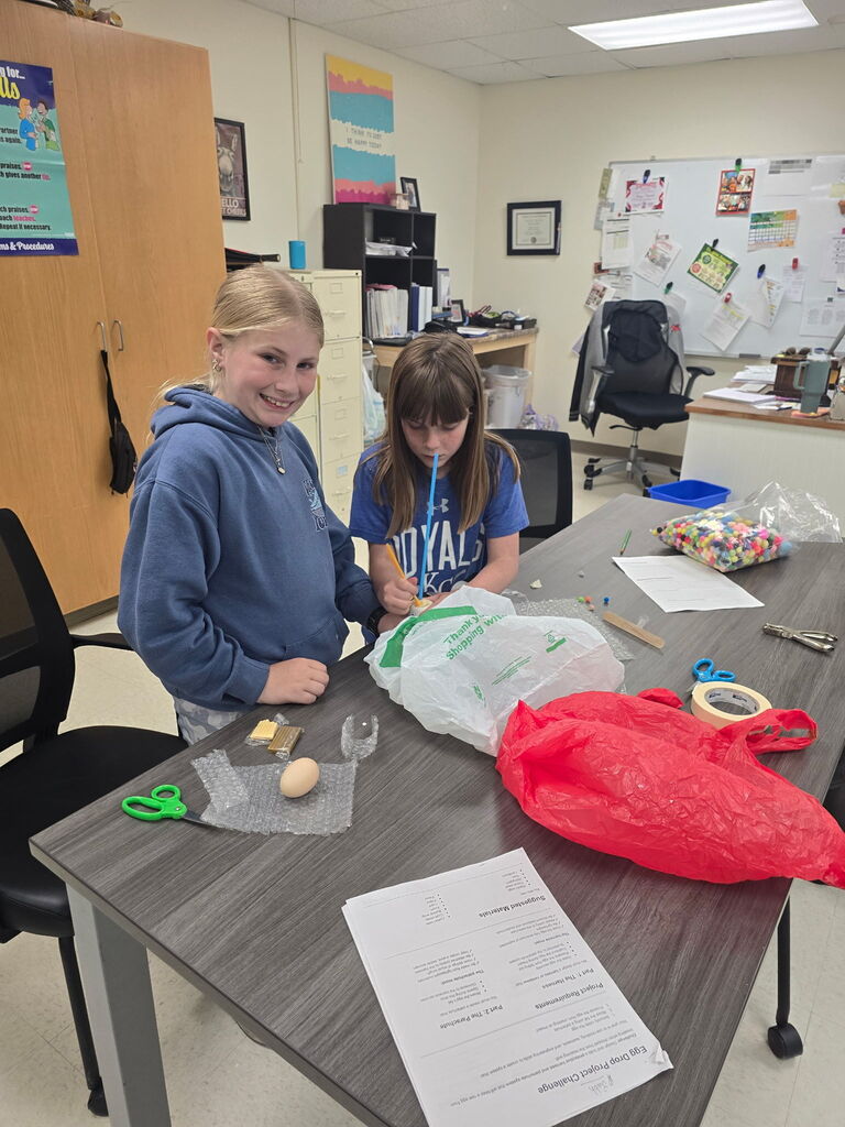 Two students with an egg and a plastic bag.