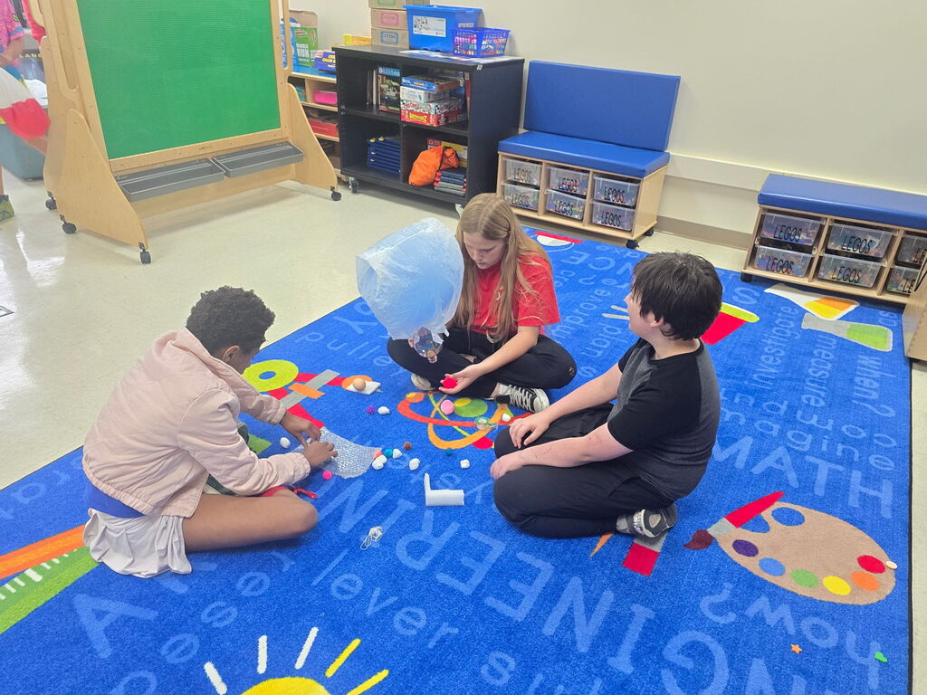 Three students working on the floor.