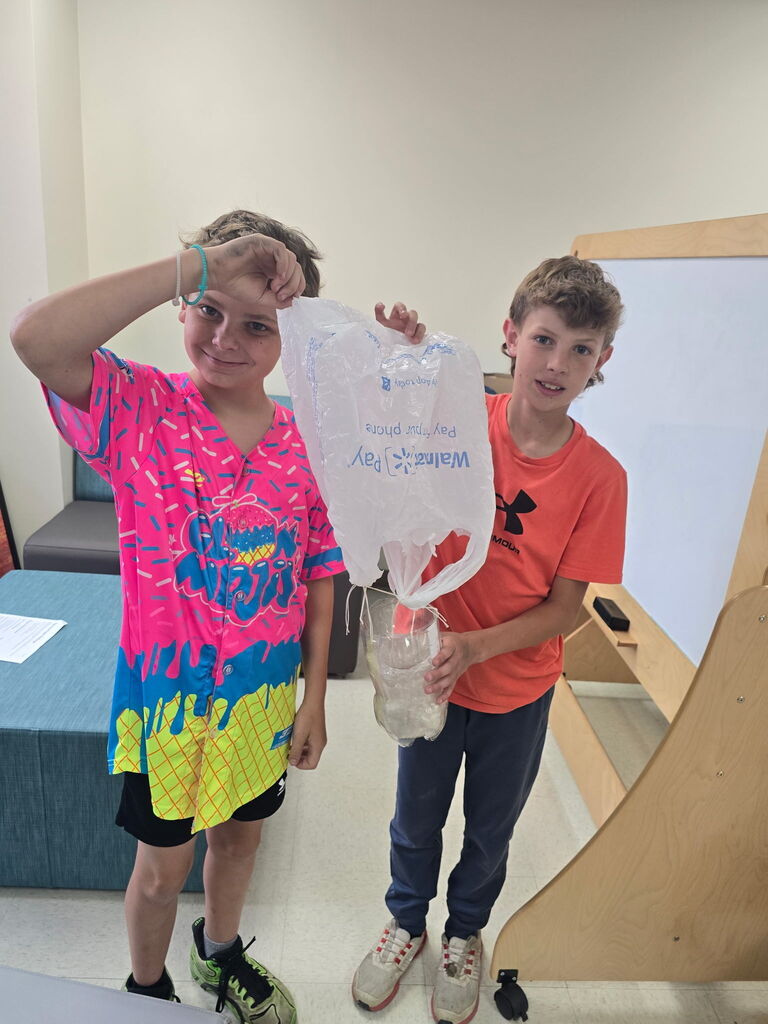 Two students holding a plastic bag
