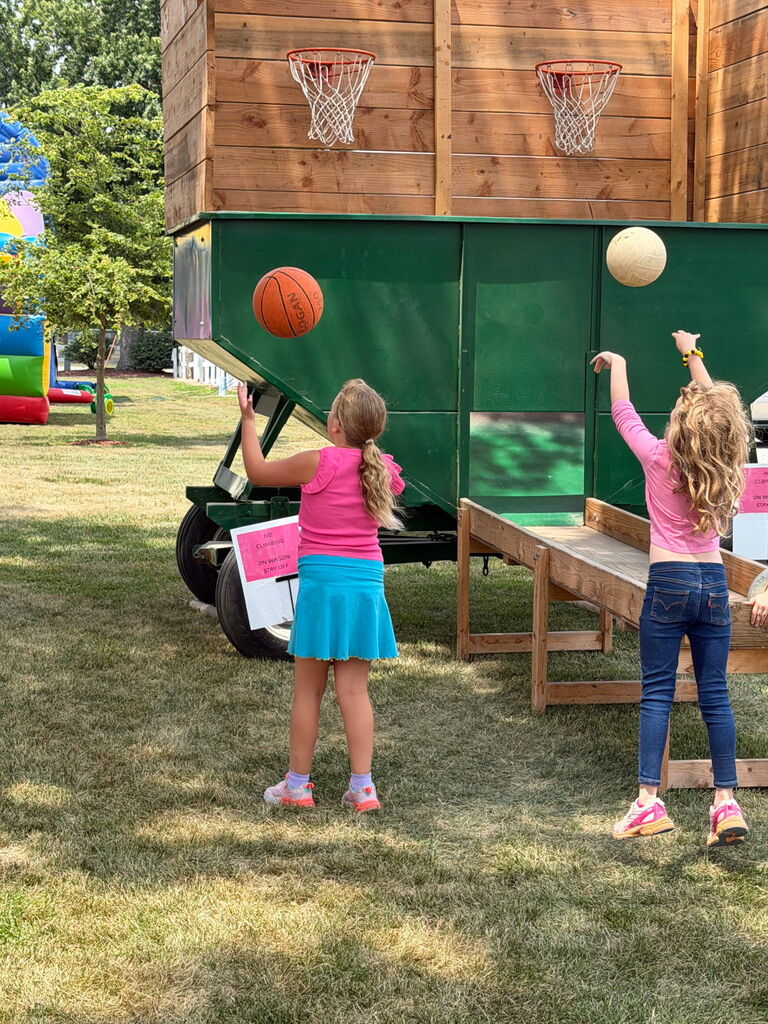 Two girls shooting basketballs into a wagon hoop