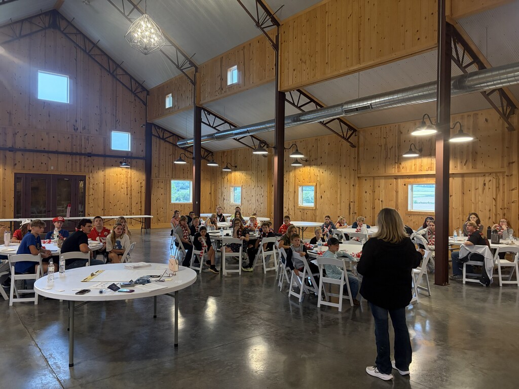 Students sitting at round tables with a woman standing