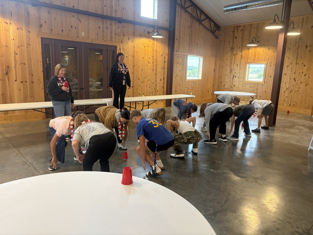 A group of students bending over with a woman in the front of the room.