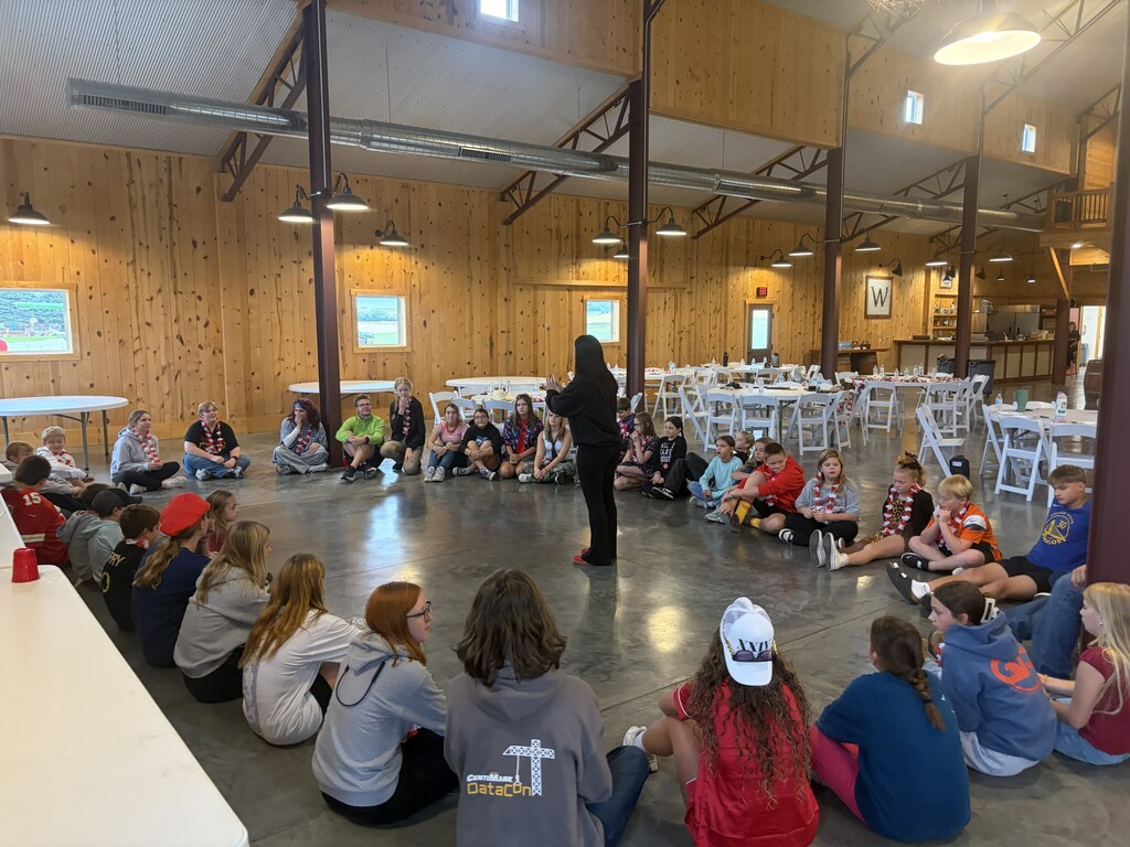 Kids sitting in a circle with a woman in the middle.