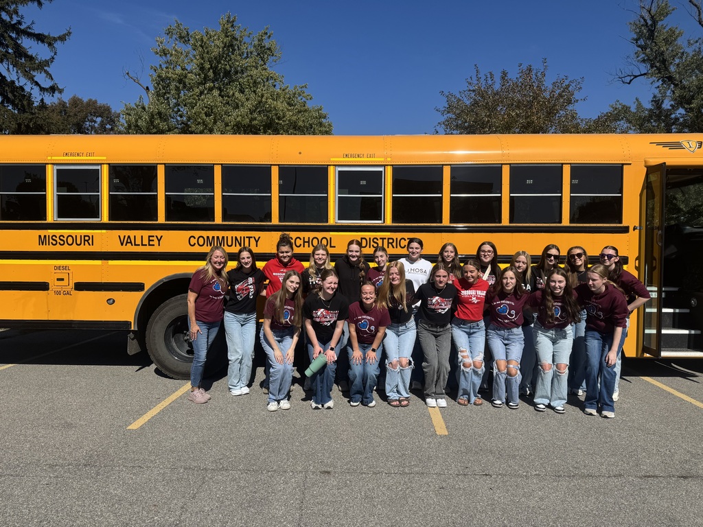 Missouri Valley students pose in front of a yellow Missouri Valley Community School District bus on a sunny day.