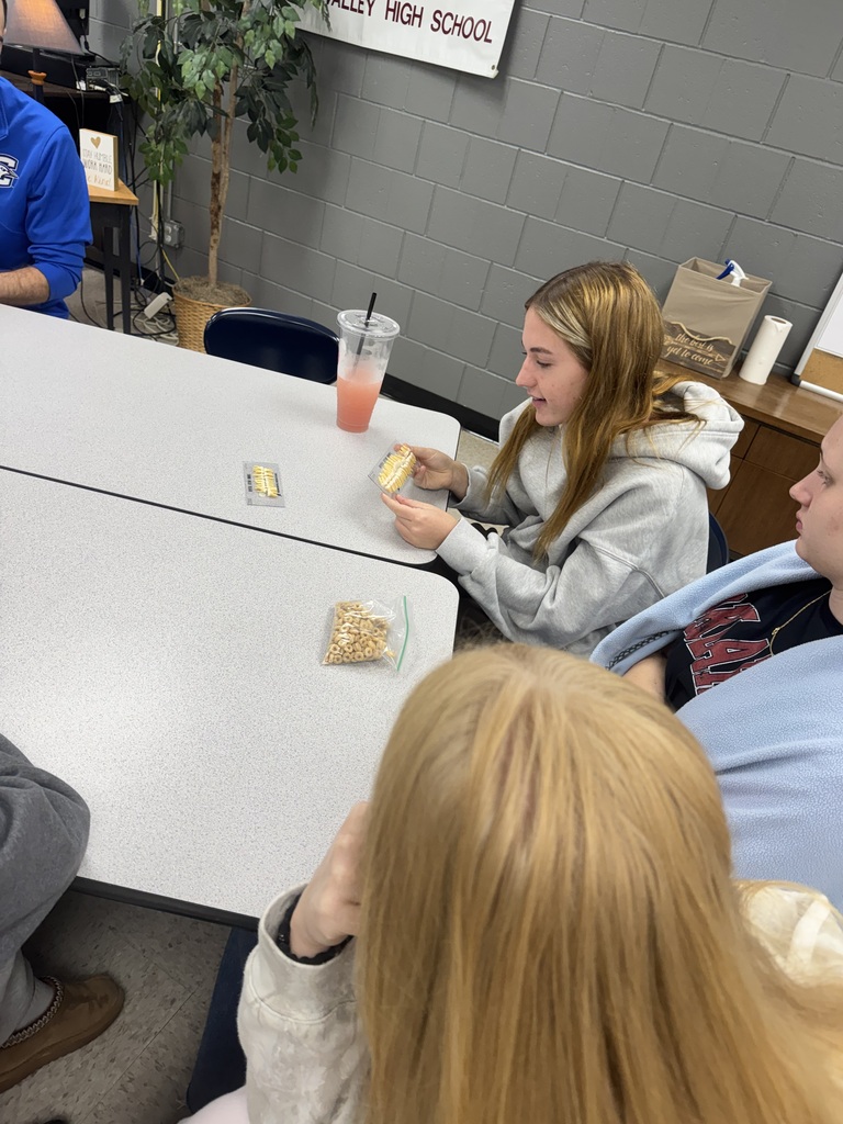 A student examines a dental shade guide to compare tooth colors while classmates observe during a dentistry lesson.