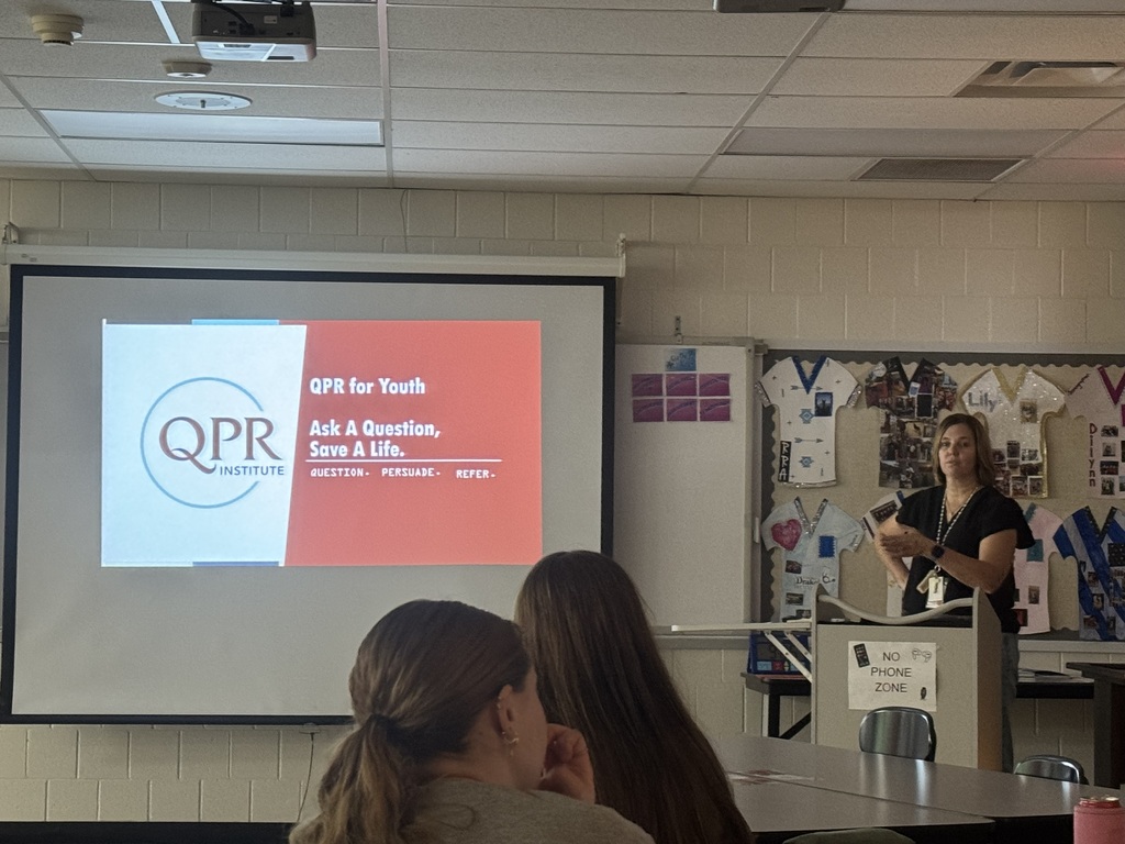 A presenter speaks to students beside a QPR for Youth slide reading, “Ask a Question, Save a Life. Question. Persuade. Refer.”
