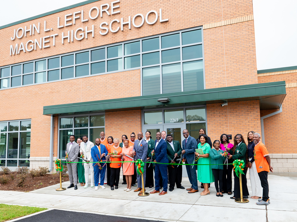 A group of people cutting a green ribbon in front of the new LeFlore Magnet High School