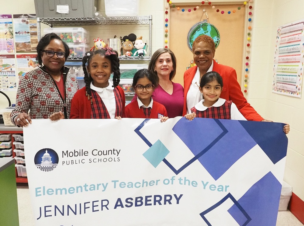 Jennifer Asberry, three Council students, the school's principal and board member stand behind a banner recognizing her as Teacher of the Year