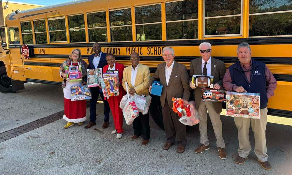 A row of people holding toys in front of a school bus