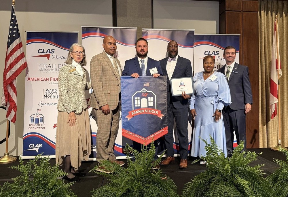 Bryant Principal David Sprinkle, MCPSS Superintendent Chresal Threadgill and other staff and board members, with the CLAS Banner School pennant