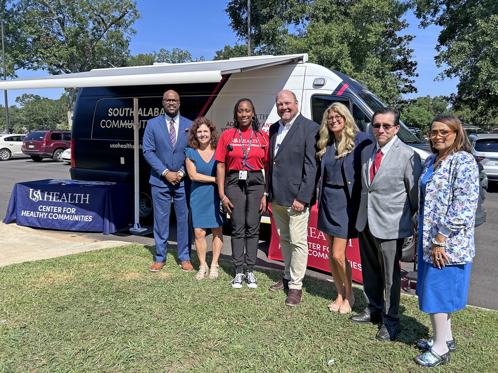 South Alabama and Mobile County Public Schools officials stand in front of a van that serves as a mobile health clinic