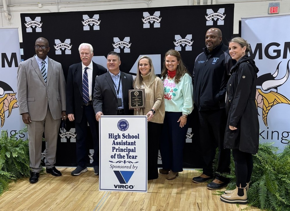 A group of people stand behind a sign that reads "High School Assistant Principal of the Year"