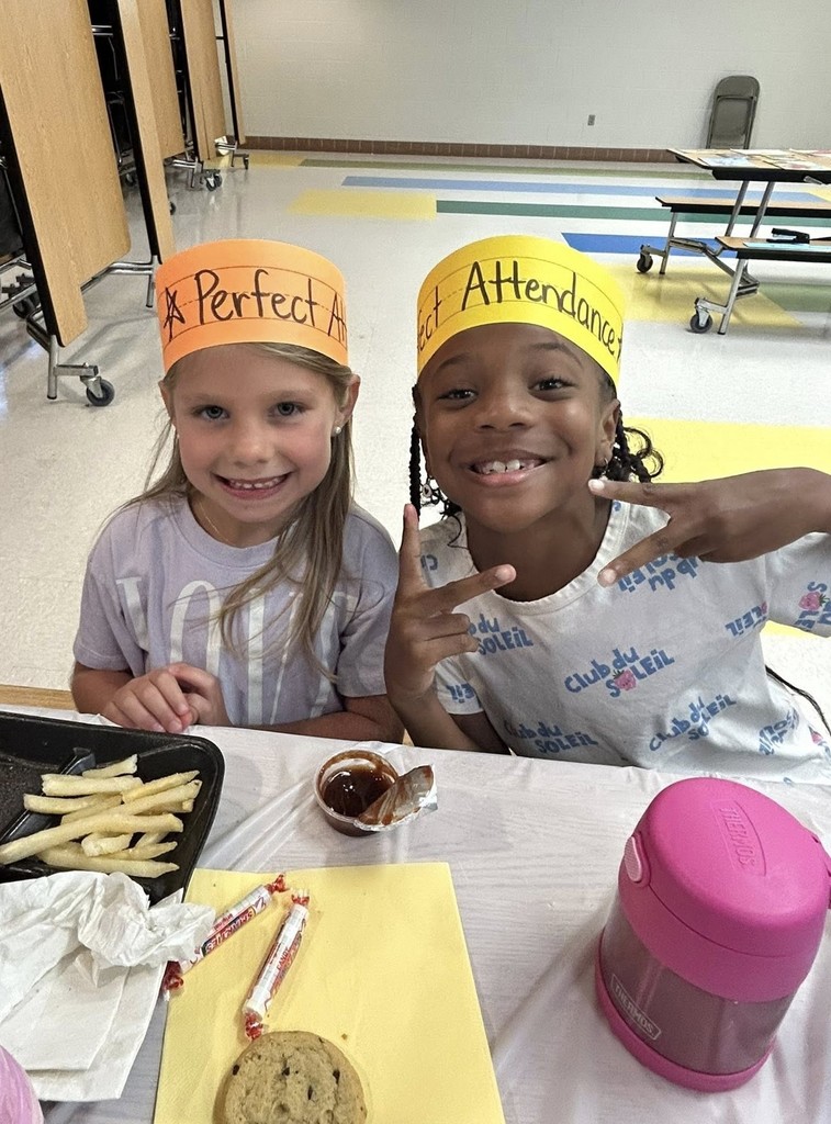 Two students with "Perfect Attendance" hats eating in a cafeteria