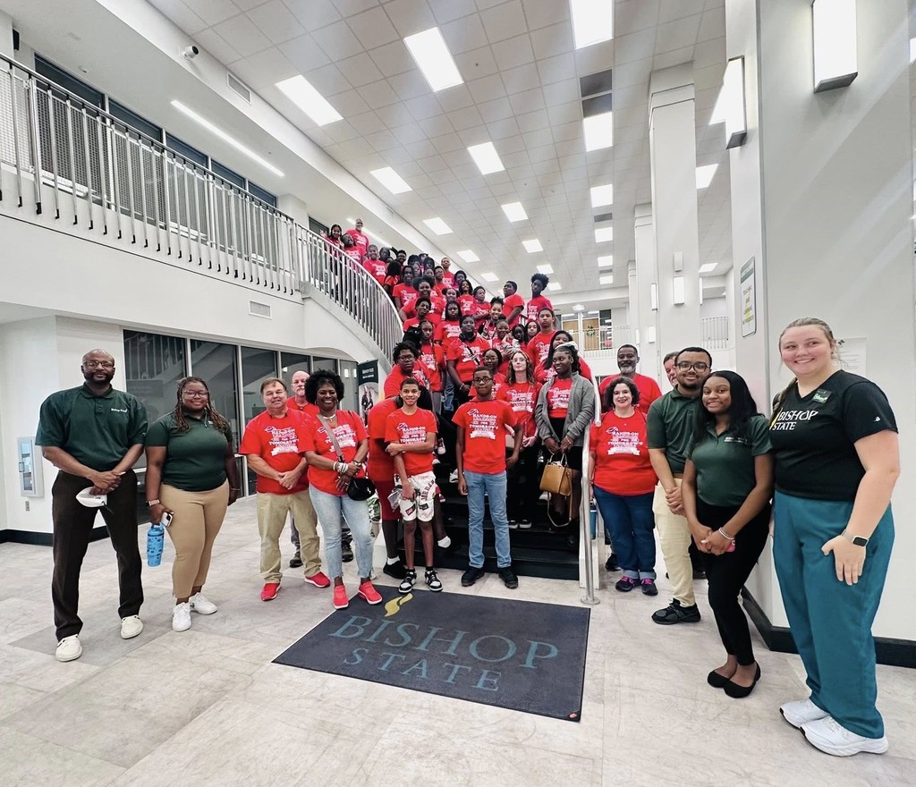 A group of students in red T-shirts standing on a stairwell at Bishop State Community College, with instructors in the foreground