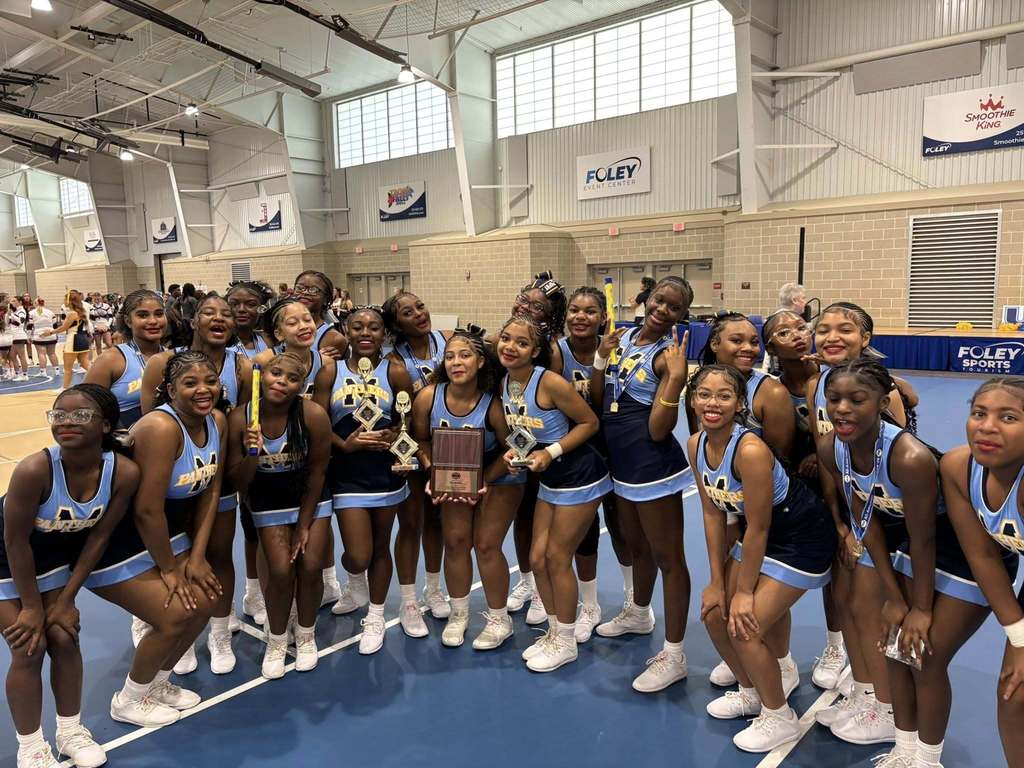 A group photo of Murphy High School cheerleaders, with three holding trophies