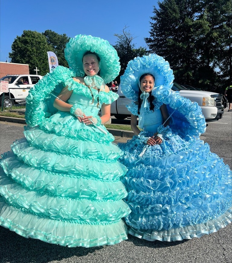 Two girls in antebellum hoop dresses, holding parasols