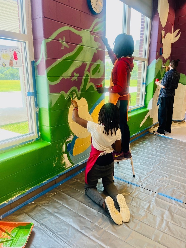 Three students painting a mural on the school walls at Chastang-Fournier K-8
