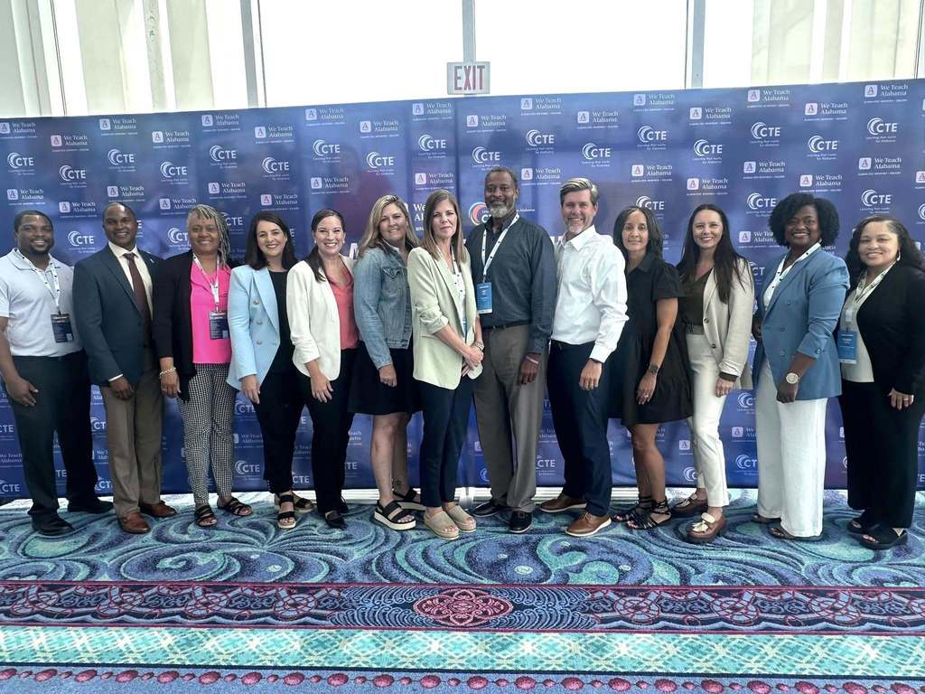 A large group of educators standing in front of a Career and Technical Education backdrop
