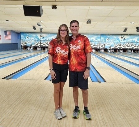 two people in bowling shirts standing in a bowling alley