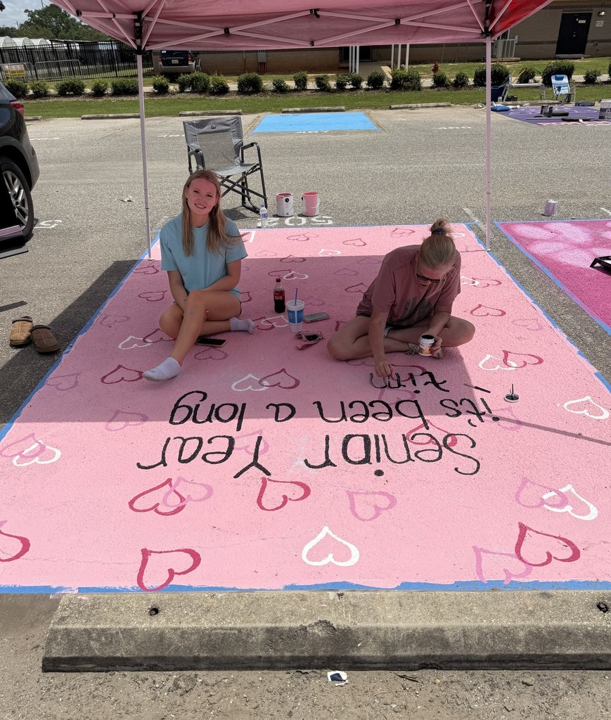 Two girls painting a parking spot in pink