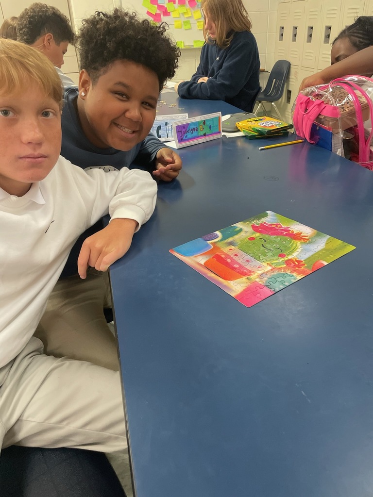 2 male students at a table with a puzzle they completed