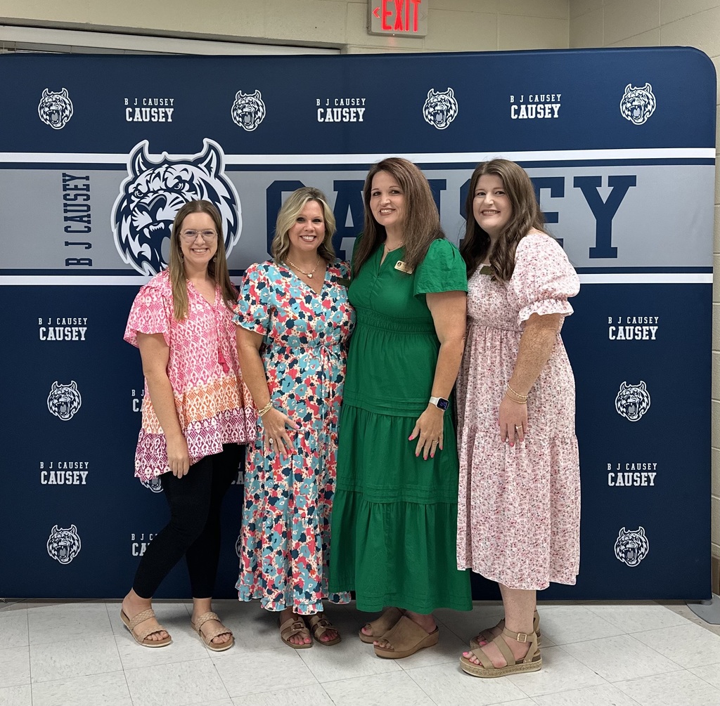 4 women standing in front of a sign posing for a photo