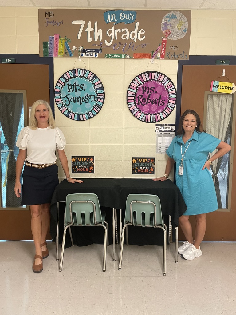 2 women standing outside classrooms posing for a picture
