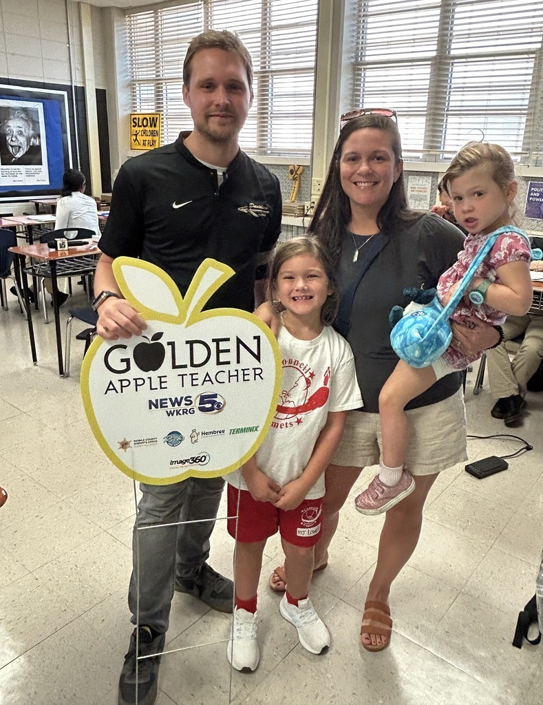 Davidson teacher Collin Lowell with his family and a Golden Apple award sign